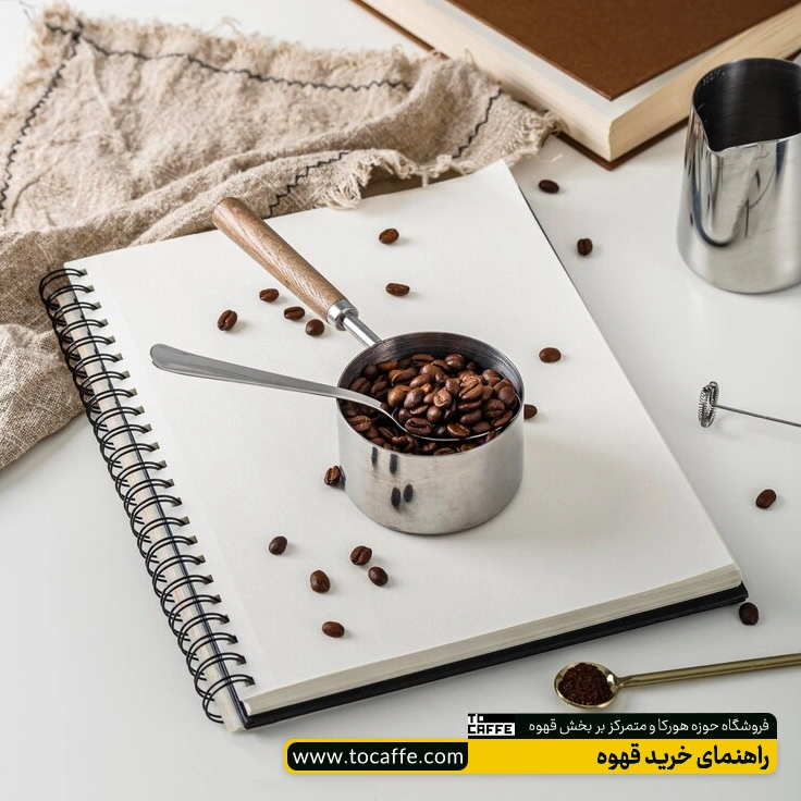 یک ظرف پر از دانه‌های قهوه روی یک دفتر قرار گرفته