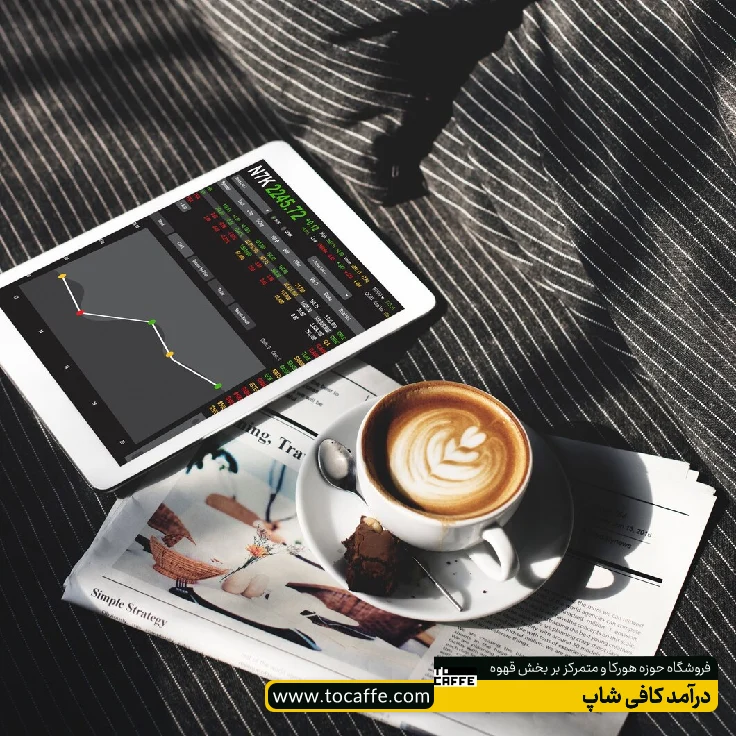 یک فنجان قهوه در کنار یک تبلت برای محاسبه درآمد کافی شاپ قرار گرفته است