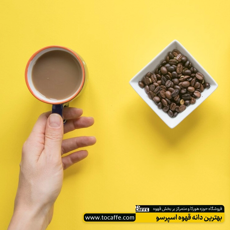 یک فنجان قهوه در کنار یک پیاله پر از دان قهوه قرار دارد